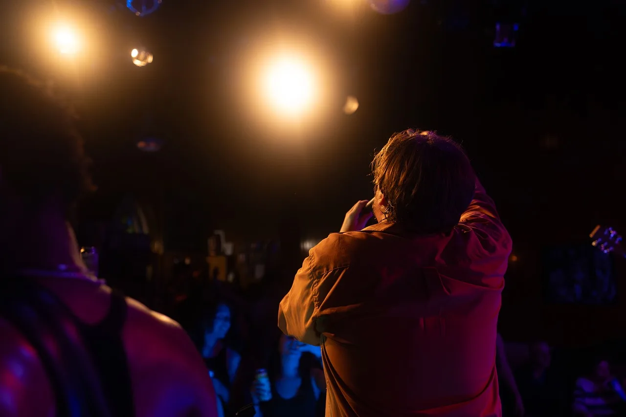 concert, singer, audience, stage, spotlight, orange, show, room, live music, entertainment, fans, atmosphere, music, microphone, energy, evening, podium, artist, performance, party, club. Corporate event planning legal and insurance guide
