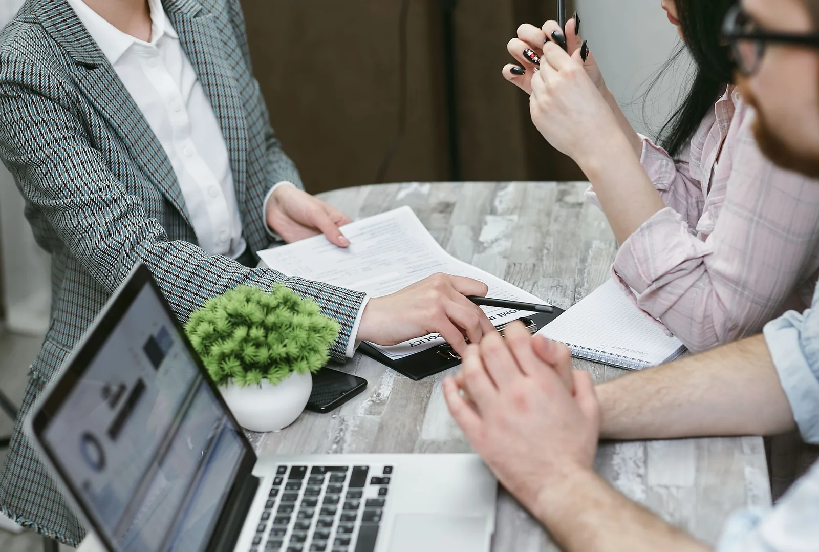 Professional meeting discussing business agreements with laptops and documents on a rustic table. Corporate event planning startup: legal setup to event chain