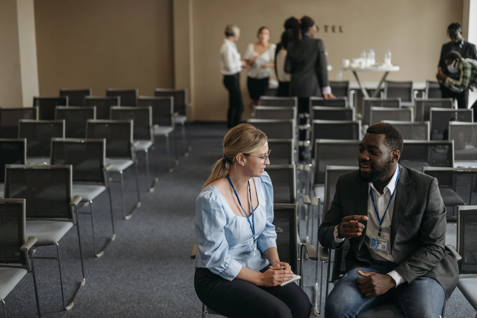 Business professionals having a conversation during a conference break, fostering communication. Which marketing channels actually bring in corporate event planning clients?
